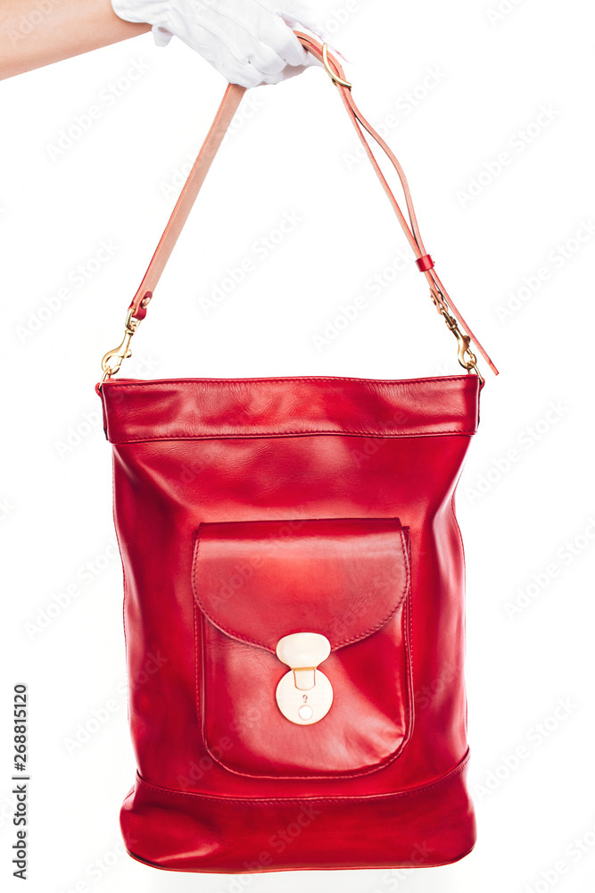 Red leather bag with a large pocket carved on a white background. bag backpack. golden headset.