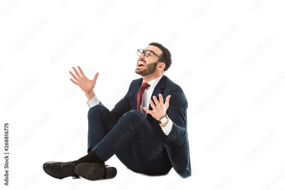 happy businessman looking up and gesturing while sitting on white background
