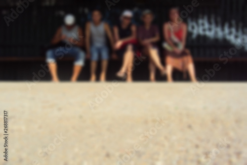 Young people sitting on a bench in a summer sunny day. Soft focus.
