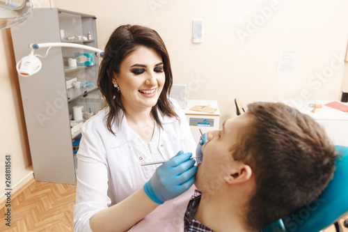 Young female dentist and her patient taking care to teeth