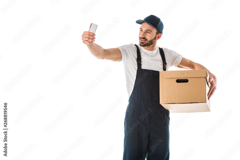 handsome delivery man taking selfie with smartphone while holding cardboard box isolated on white handsome delivery man taking selfie with smartphone while holding cardboard box isolated on white