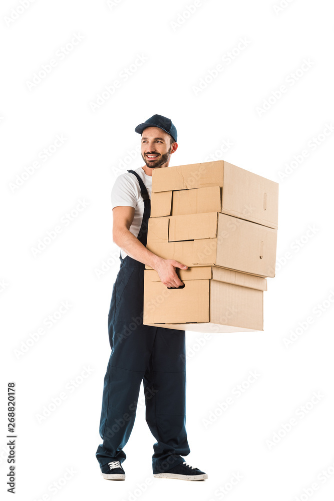 smiling delivery man carrying cardboard boxes and looking away isolated on white smiling delivery man carrying cardboard boxes and looking away isolated on white