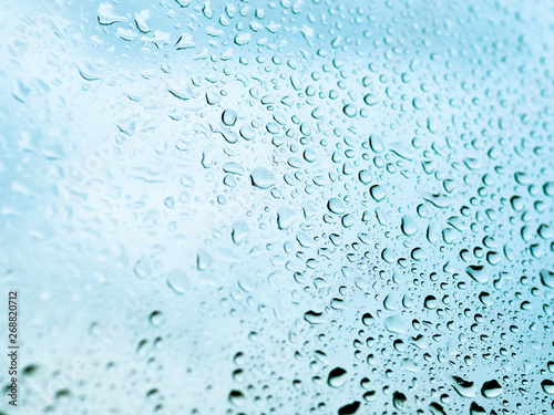 Rain drops on glass. Silhouettes of light blue water drops on a transparent surface.