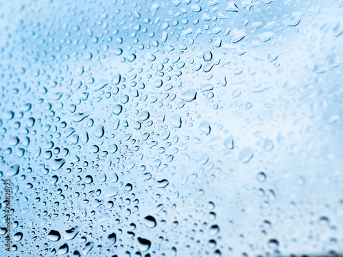 Rain drops on glass. Silhouettes of light blue water drops on a transparent surface.