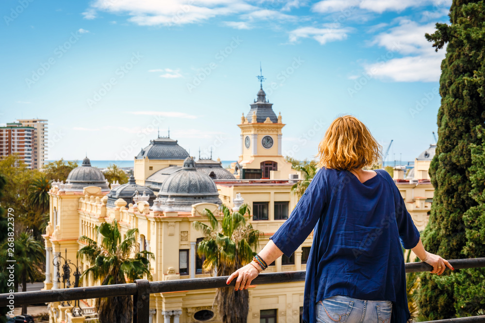 woman with blue shirt enjoys the view over the town of Malaga, Spain - obrazy, fototapety, plakaty 
