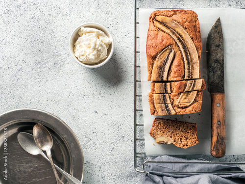 Butter-free, sugar-free banana bread with oat flour, soft curd cheese and honey. Top view of sliced banana bread on gray cement background. Ideas and recipes for healthy diet breakfast photo