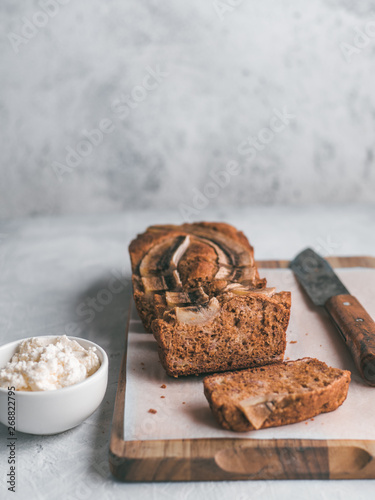 Butter-free,sugar-free banana bread with oat flour,soft curd cheese,honey.Side view sliced banana bread on wooden cutting board.Copy space.Ideas recipe healthy diet breakfast. Selective focus.Vertical photo