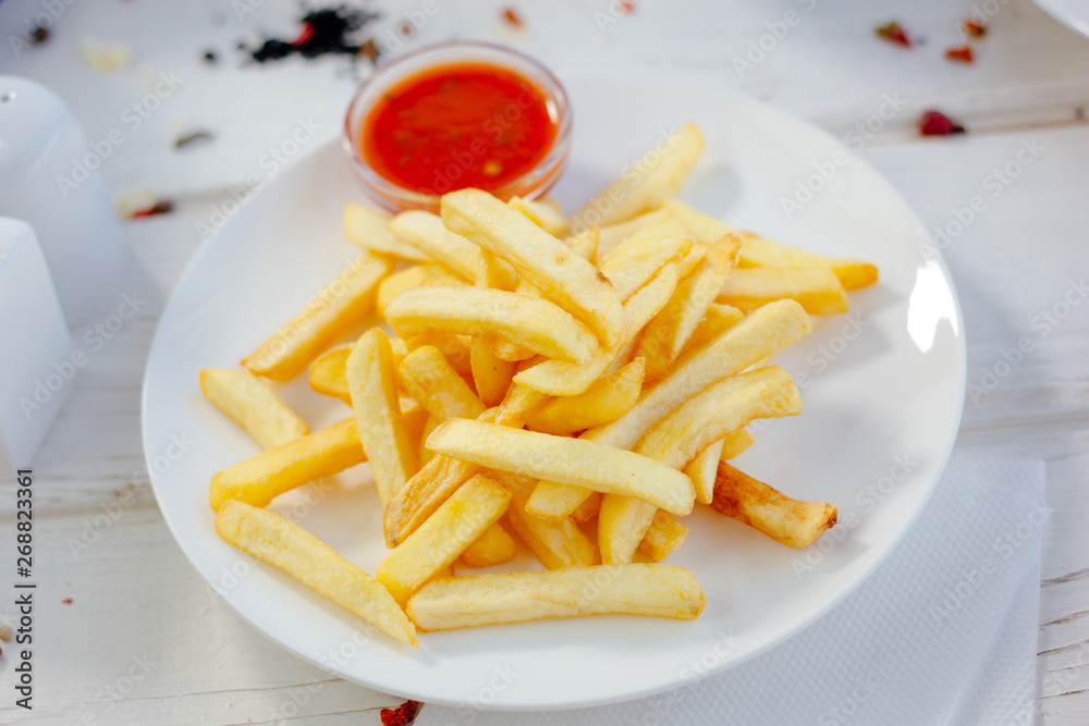 French fries with red tomato sauce on the white plate. French fries with red tomato sauce on the white plate.