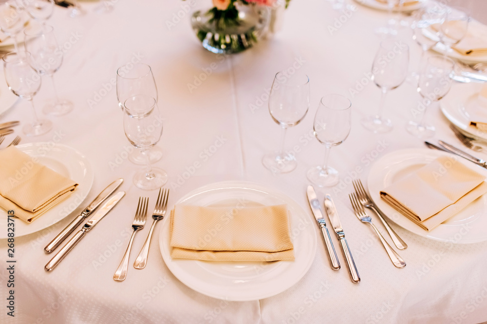 table setting. white porcelain plate on a white tablecloth with a napkin. table setting. white porcelain plate on a white tablecloth with a napkin.