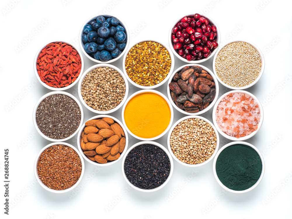 Various superfoods in smal bowl isolated on white background. Superfood as chia, spirulina, raw cocoa bean, goji, hemp, quinoa, bee pollen, black sesame, turmeric. Top view or flat-lay.