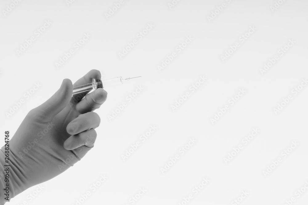 Hand in a blue glove holding medical syringe on black and white Hand in a blue glove holding medical syringe on black and white