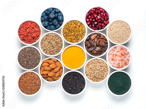 Various superfoods in smal bowl isolated on white background. Superfood as chia  spirulina  raw cocoa bean  goji  hemp  quinoa  bee pollen  black sesame  turmeric. Top view or flat-lay.
