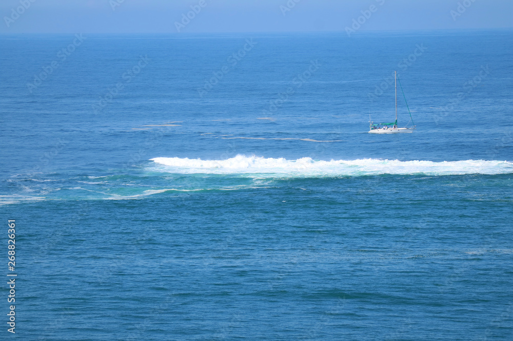 Beautiful blue ocean with the crashing waves and a white yacht Beautiful blue ocean with the crashing waves and a white yacht
