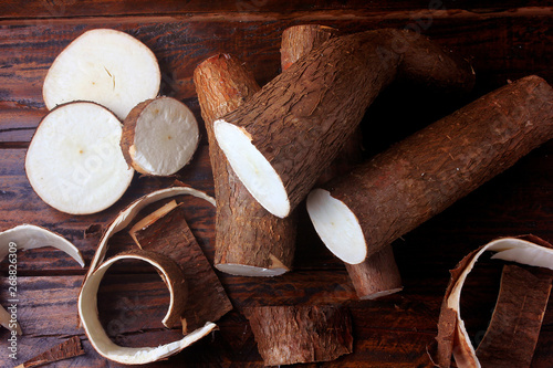 fresh cassava and peels and slices on rustic wooden table photo