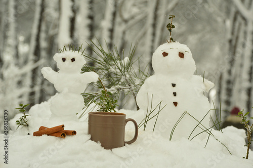 Cup of coffee on the snow with snowmans 