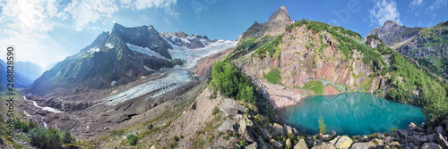 Panoramic view of the mountain peaks, glacier and lake. Caucasus Mountains, Dombay. 