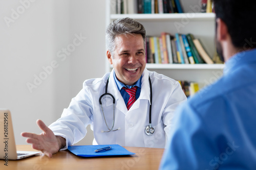 Sympathischer Arzt mit Patient bei der Sprechstunde photo