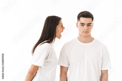 Angry young couple standing isolated over white background