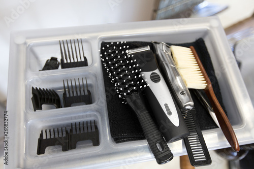 hair tools, grooming and hairdressing concept - brushes, trimmers and comb on tray at barbershop