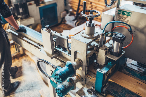 The worker in the woodworking workshop manually sorts and supplies the material to the machine - conveyor production