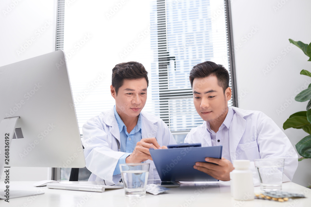 Obraz premium Two doctors holding and talking about patient on office