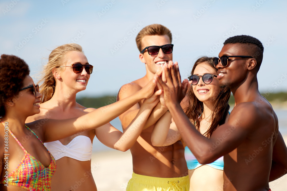 friendship, summer holidays and people concept - group of happy friends making high five on beach friendship, summer holidays and people concept - group of happy friends making high five on beach
