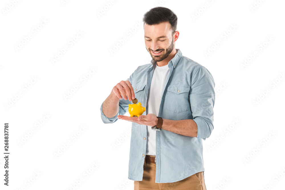 smiling handsome man putting coin into moneybox isolated on white smiling handsome man putting coin into moneybox isolated on white