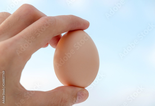 Egg in hand at the background of the sky