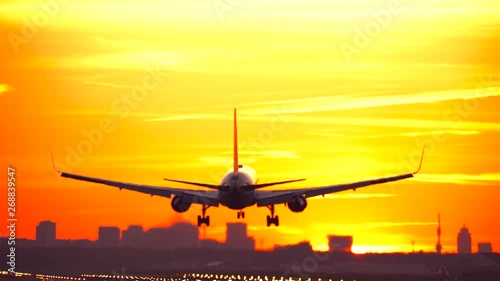 Airplane landing at sunrise with skyline 