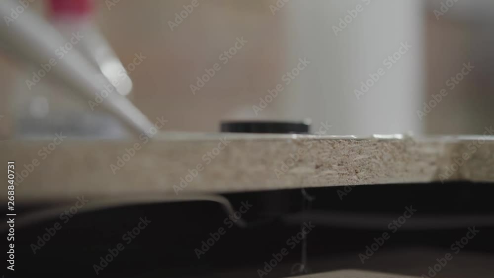 The worker putting silicone glue on the MDF board close up. Profession of the carpenter. Concept of hand manufacturing. Furniture producing. The worker putting silicone glue on the MDF board close up. Profession of the carpenter. Concept of hand manufacturing. Furniture producing.