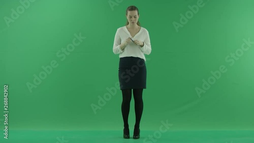 a thoughtful woman is thinkig, getting the idea grinding retractable ballpoint pen. She wears formal dress: white shirt and blak skirt. Lady stands front in the centre of a green screen photo