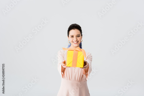 beautiful stylish young woman holding present and smiling isolated on grey