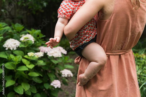 Mother holding baby in garden