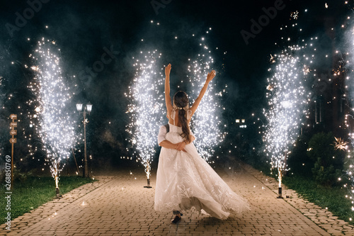 beautiful happy young wedding couple dancing outdoor between fireworks photo