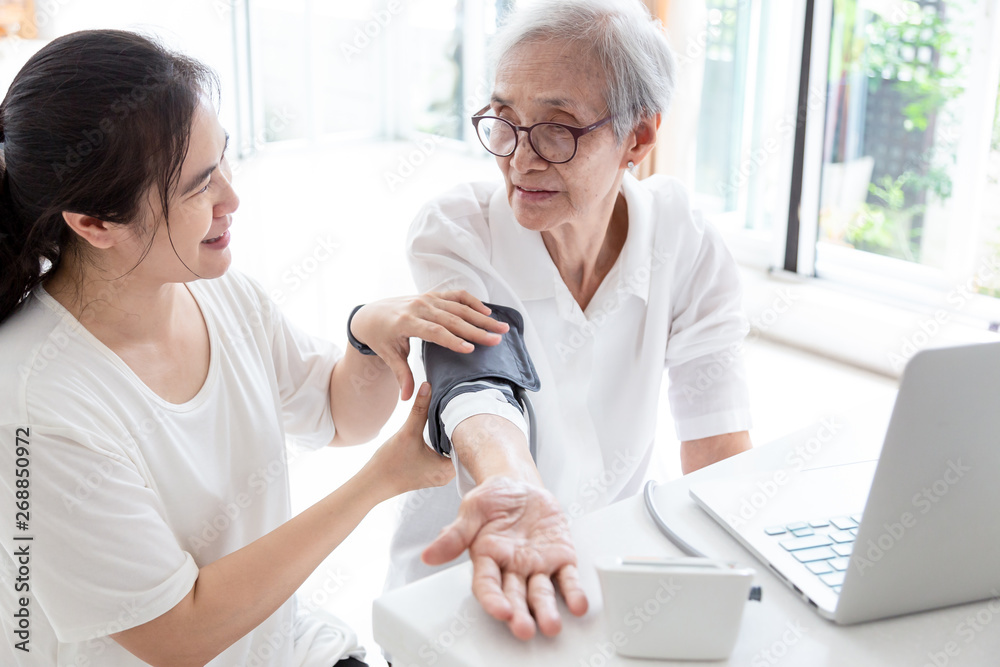 Obraz premium Female nurse checking blood pressure of a senior woman at home,asian elderly people check health,Home carer checking patients blood pressure