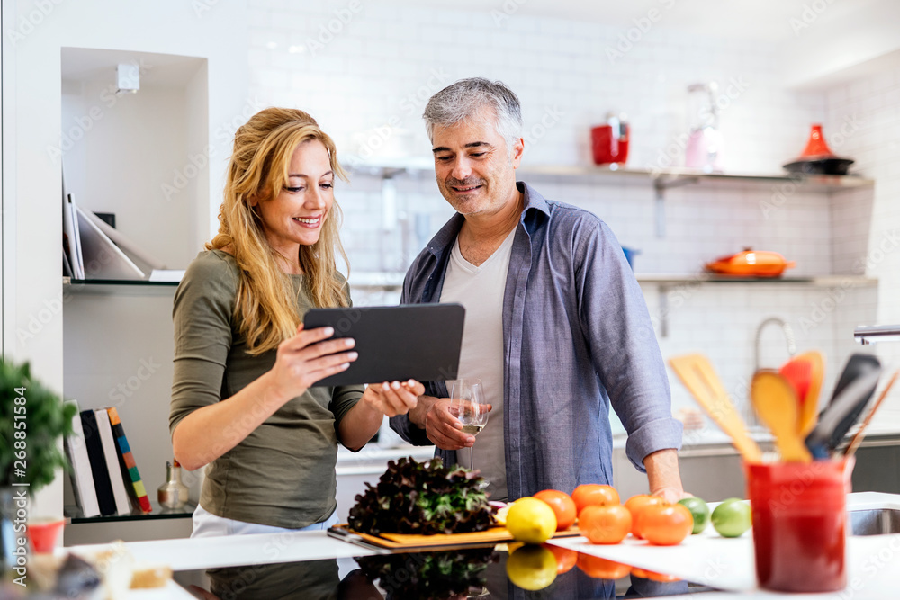 Married couple using tablet in the kitchen Married couple using tablet in the kitchen