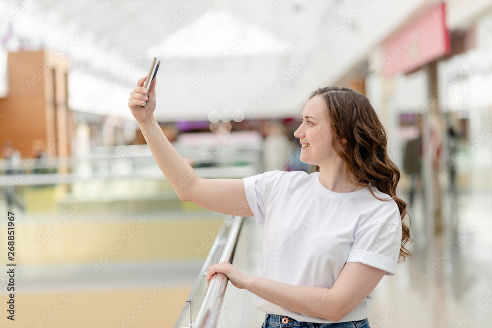 Young woman with phone in her hand making selfie. Portrait, happy smile, beauty and technology concept