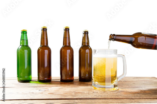 Glass and bottle of beer with no logos on wooden table isolated copy space, bottle mock up. Beer bottle studio shot with cap isolated.