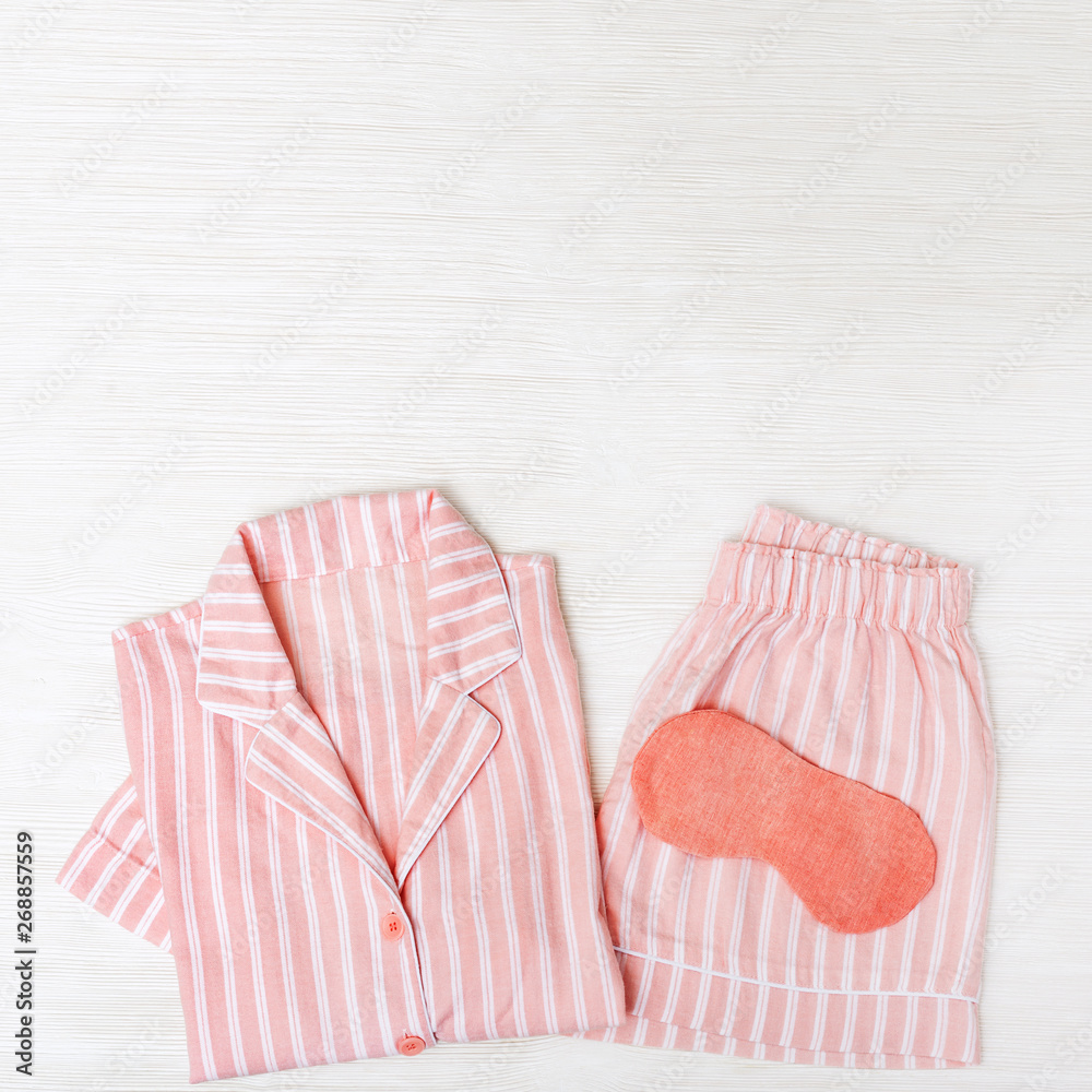 Pink pajamas for Girls, eye mask for sleeping on white wood. Top view. Flat lay. Pink pajamas for Girls, eye mask for sleeping on white wood. Top view. Flat lay.