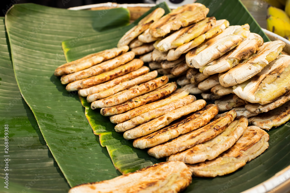 BBQ Banana on electronic fire heat oven, medium grill stack green banana leaf ready to sell, Thai Style sweet dessert for Street Food BBQ Banana on electronic fire heat oven, medium grill stack green banana leaf ready to sell, Thai Style sweet dessert for Street Food