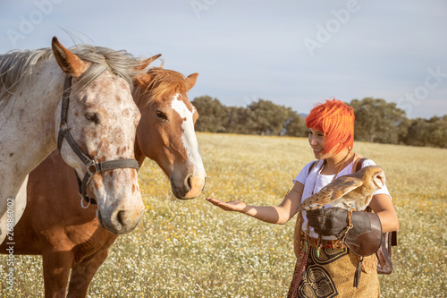 Woman with a white owl on her arm and near of horses © Gelpi