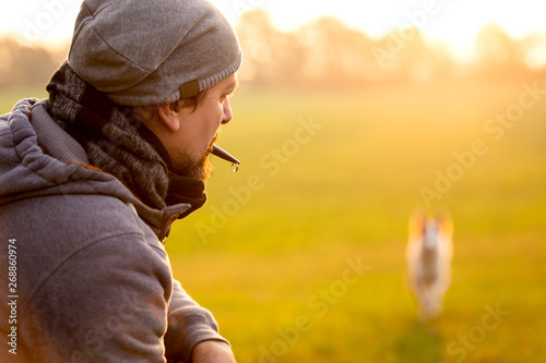 Erziehung und Training mit der Hundepfeife, Mann ruft Hund zurück photo