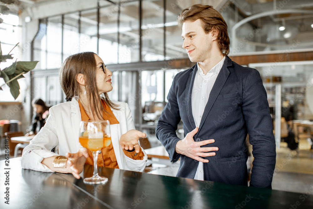 Businessman flirting with young woman sitting with cocktail at the bar Businessman flirting with young woman sitting with cocktail at the bar