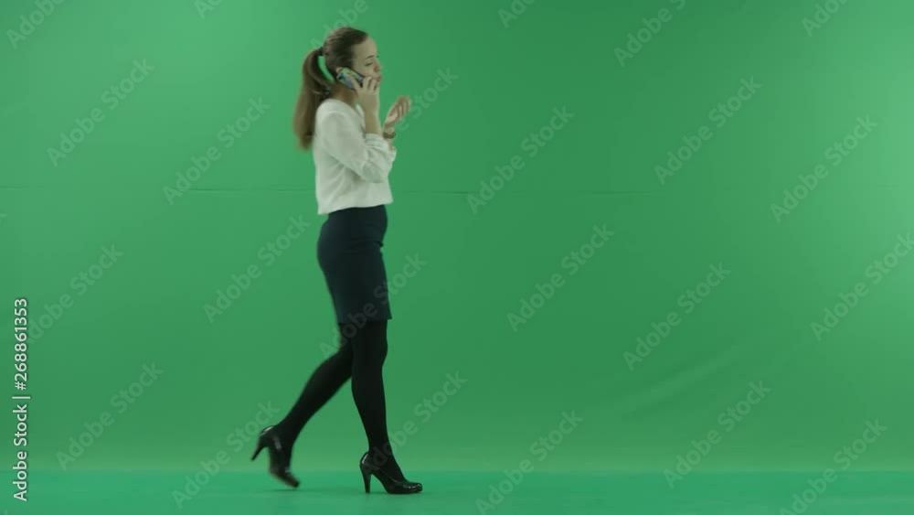 business woman is talking on her mobile cell phone and walking. She wears formal dress: white shirt and blak skirt . Businesswoman is over green screen business woman is talking on her mobile cell phone and walking. She wears formal dress: white shirt and blak skirt . Businesswoman is over green screen