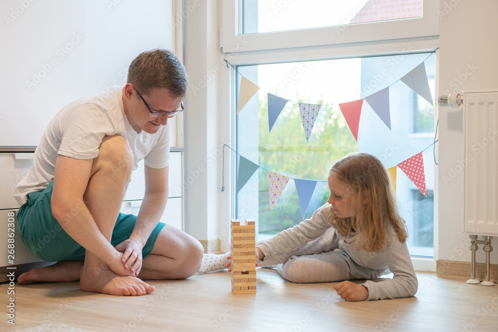 Young happy father playing with his cute daughter with wooden blocks Young happy father playing with his cute daughter with wooden blocks