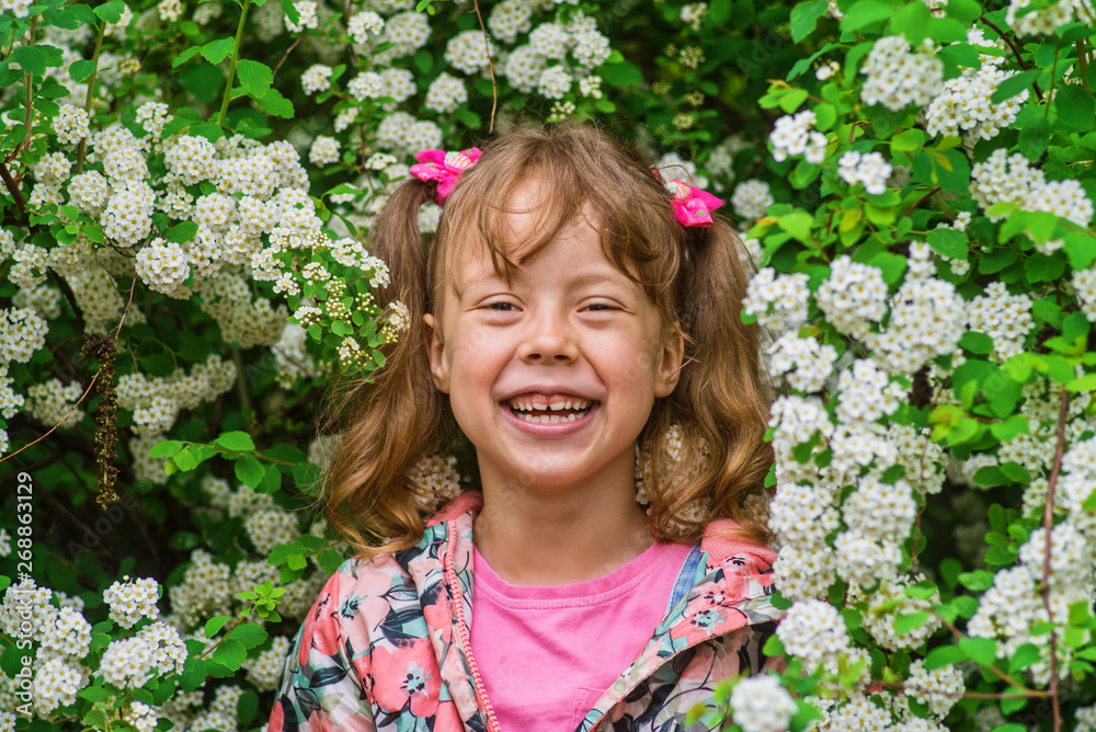 Smiling little girl about 6 years on a background of white flowers. Smiling little girl about 6 years on a background of white flowers.