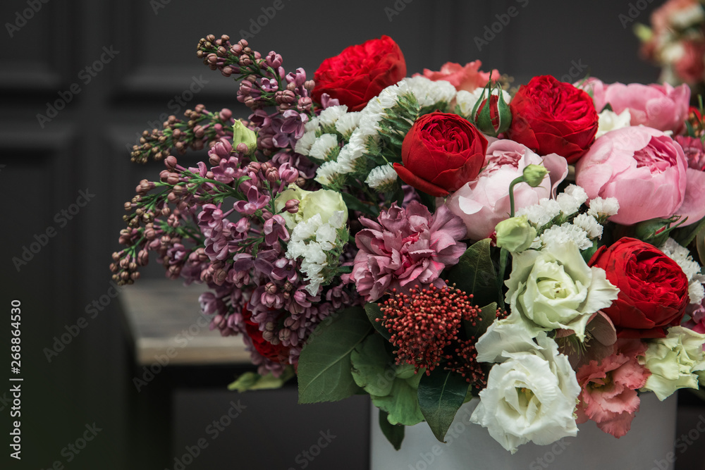 Bouquet of different beauty flowers in round present box on dark background