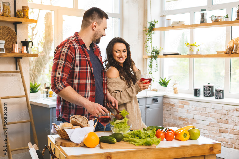 Beautiful young smiling happy couple is talking and smiling while cooking healthy food in kitchen at home. Beautiful young smiling happy couple is talking and smiling while cooking healthy food in kitchen at home.