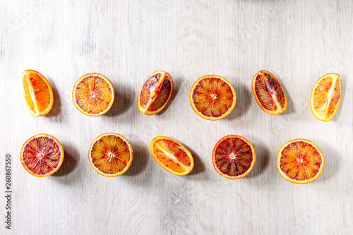 Group of fresh organic Sicilian blood oranges sliced and whole in row over white wooden background. Flat lay, space