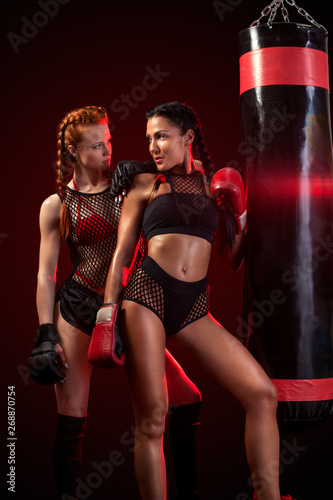 Two sexy women sportsman boxer doing boxing training at the gym. Girl wearing gloves, sportswear and hitting the punching bag.